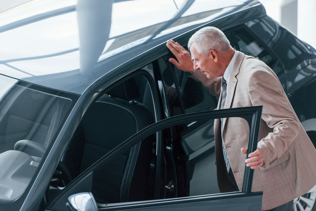 a man stands beside an open vehicle door while inspecting the interior of a modern car